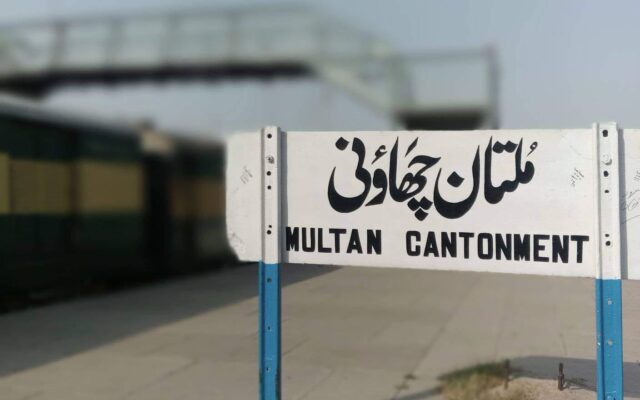 Multan Cantonment railway station signboard with a Pakistan Railways passenger train standing at the platform in Multan, the city near which the Rehman Baba Express derailed