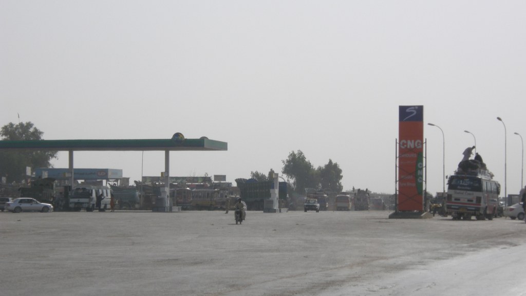 A PSO petrol station forecourt in Hyderabad, Pakistan, with trucks and a passenger bus
