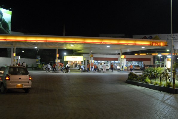 A Shell petrol station in Karachi at night with motorists refuelling their cars and motorcycles
