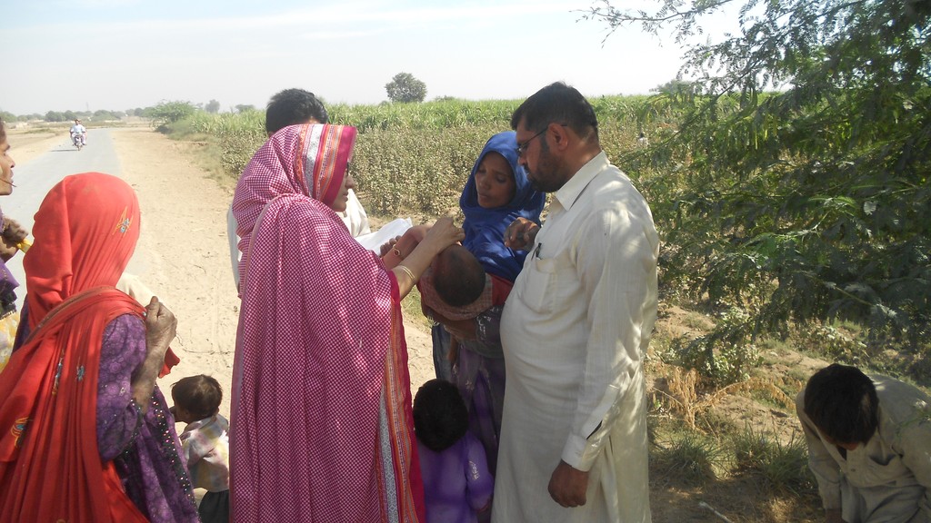 A health worker giving polio vaccine drops to a baby held by its mother during a vaccination campaign in Pakistan