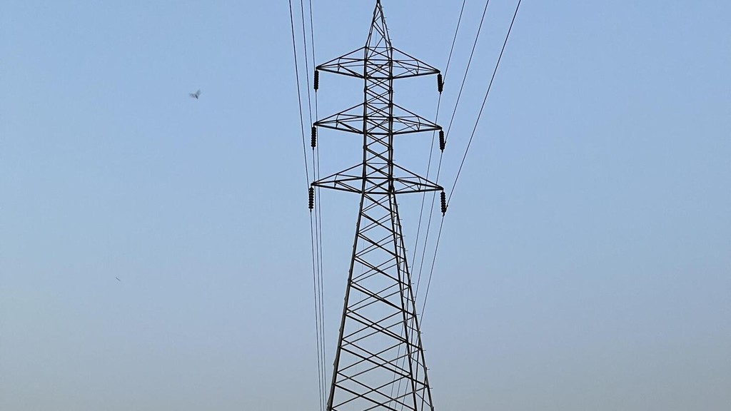A high-voltage electricity pylon carrying transmission lines against the sky in Pakistan.