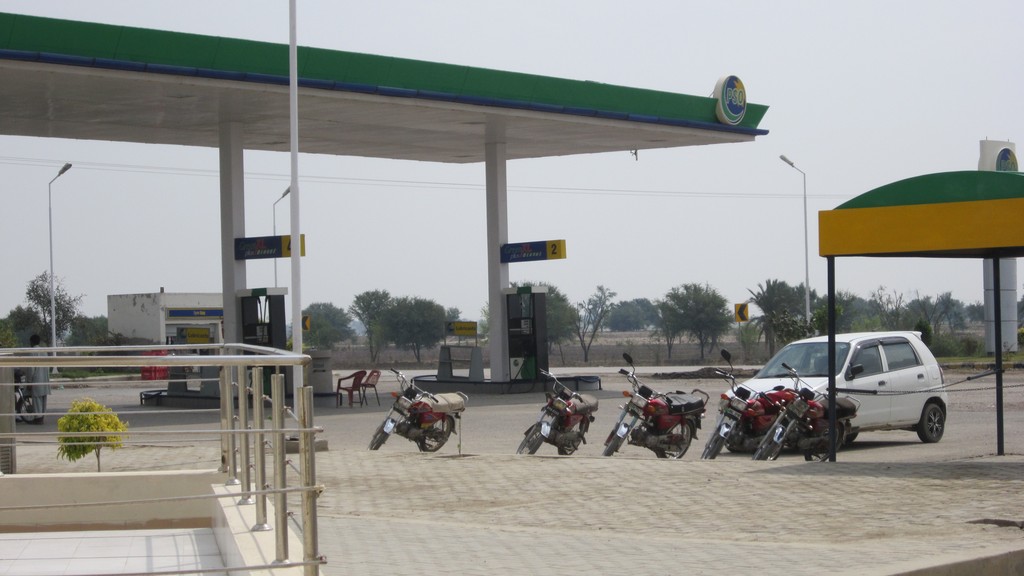 A PSO petrol station forecourt in Pakistan with a few motorcycles and a car and no queues at the pumps