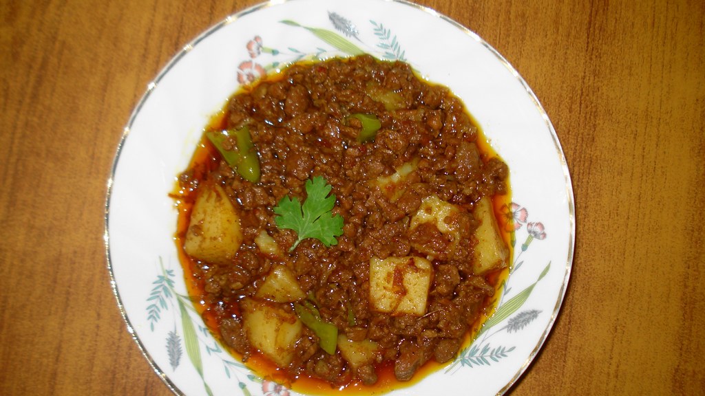 A plate of aloo keema with potato chunks and green chillies, garnished with coriander, the dish prepared using this recipe