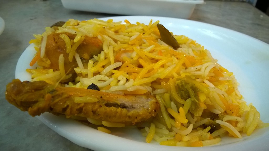 A plate of chicken biryani with layered yellow and white basmati rice and a chicken drumstick, the dish prepared at home using this recipe