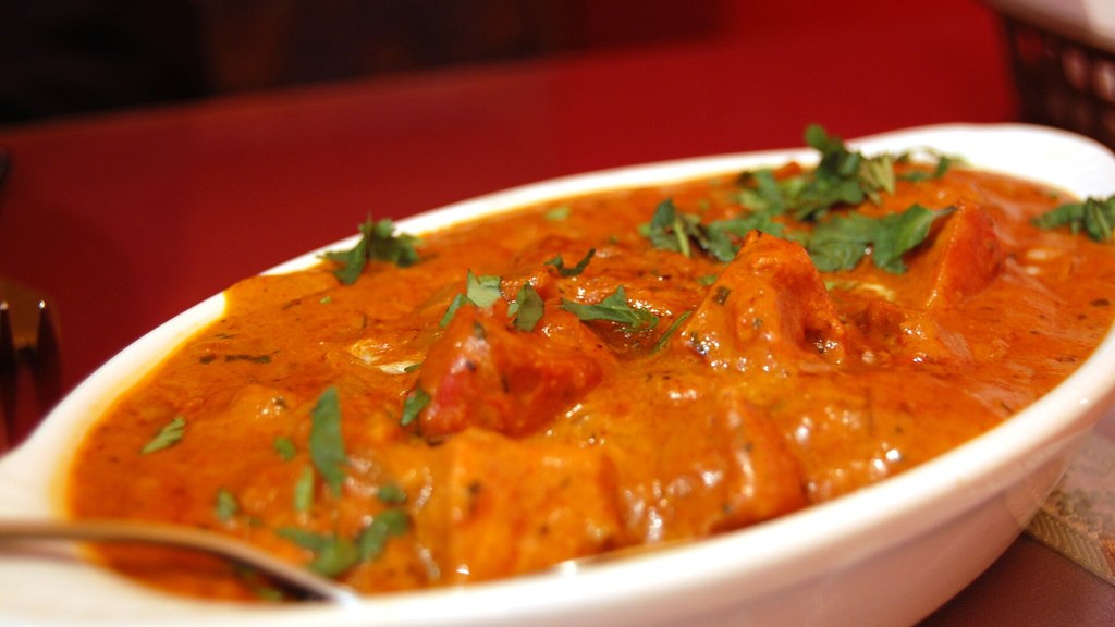A bowl of butter chicken in a rich tomato and butter makhani gravy garnished with cream and coriander, the dish prepared using this butter chicken recipe