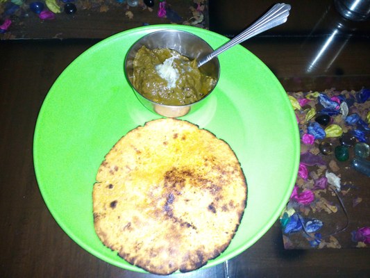 A plate of sarson ka saag topped with white butter served with makki ki roti, the classic Punjabi winter dish