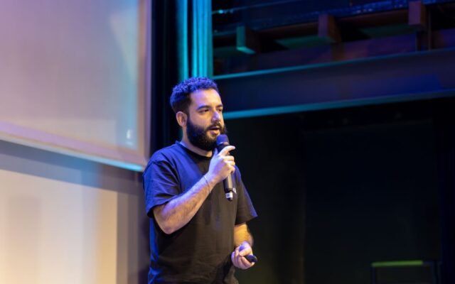 A speaker addressing the audience on stage during a technology conference
